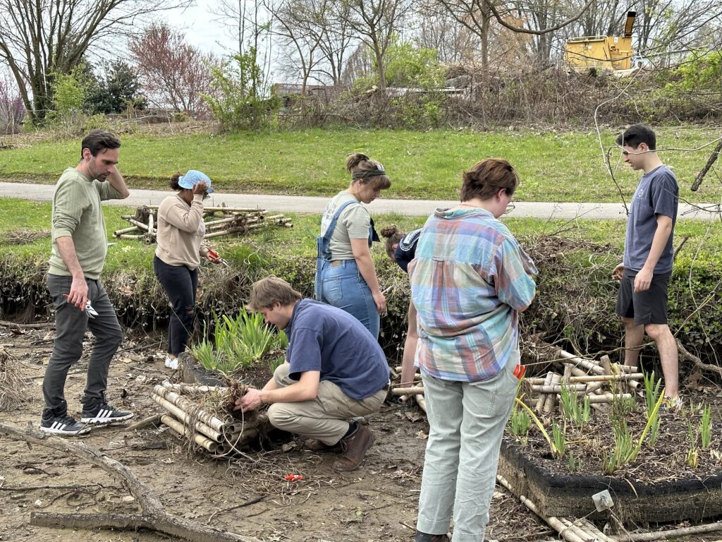 Group of students work on floating wetlands in a creekbed